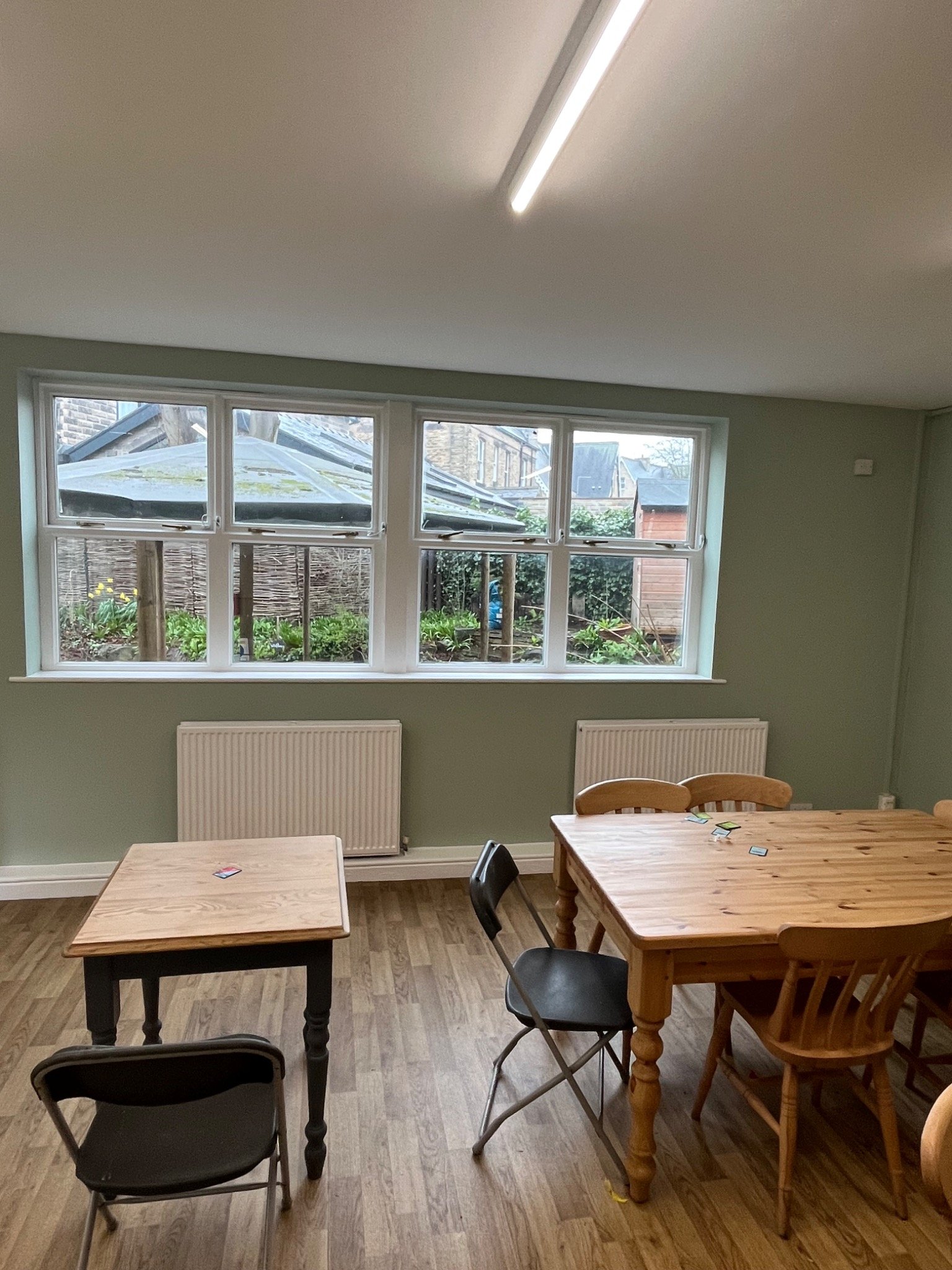Green-toned dining room with timber tables and large windows