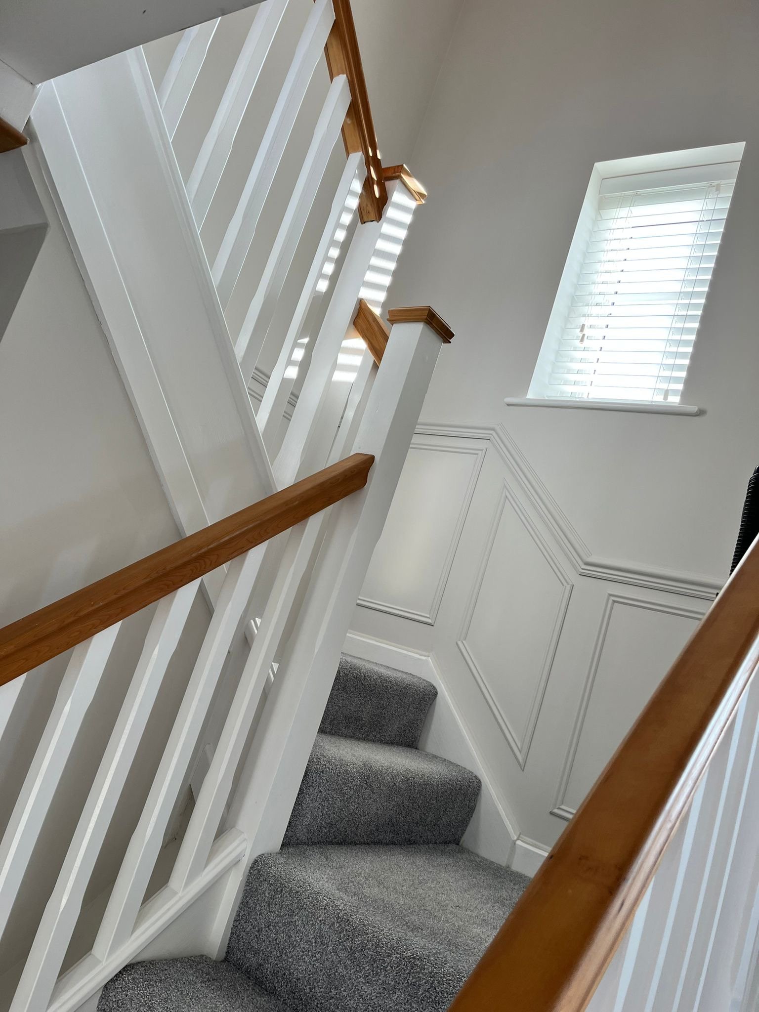 Freshly finished staircase with white balustrade and decorative wall panelling